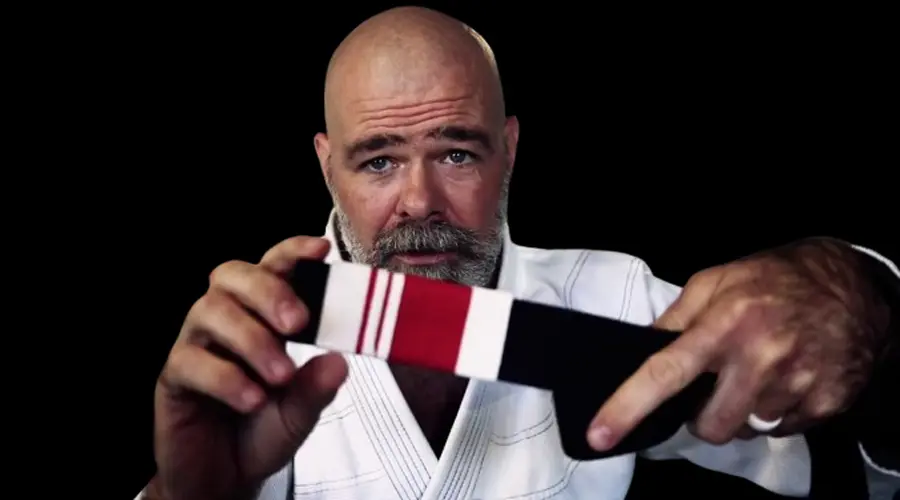 BJJ Black belt holding a BJJ Black belt with two stripes on it