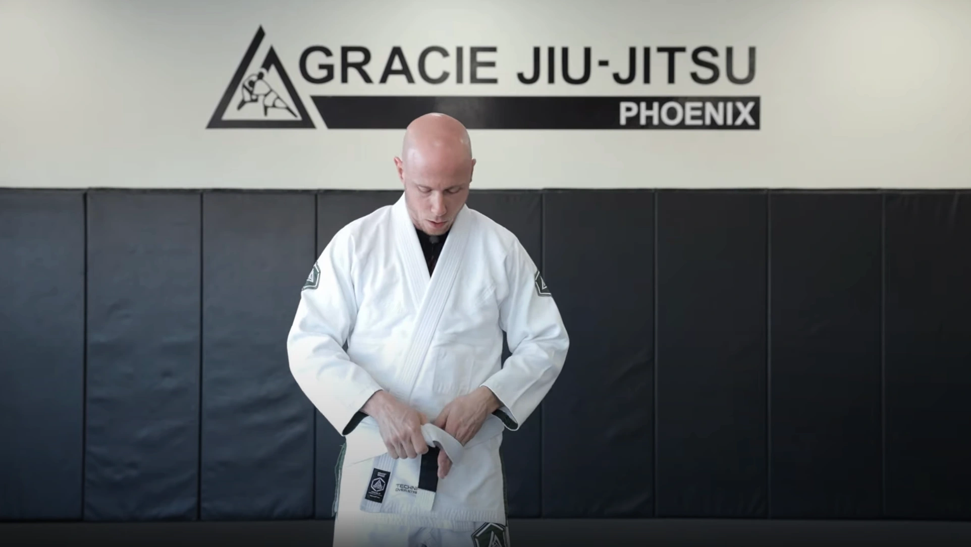 Pulling the black-bar end of the BJJ belt through the loop